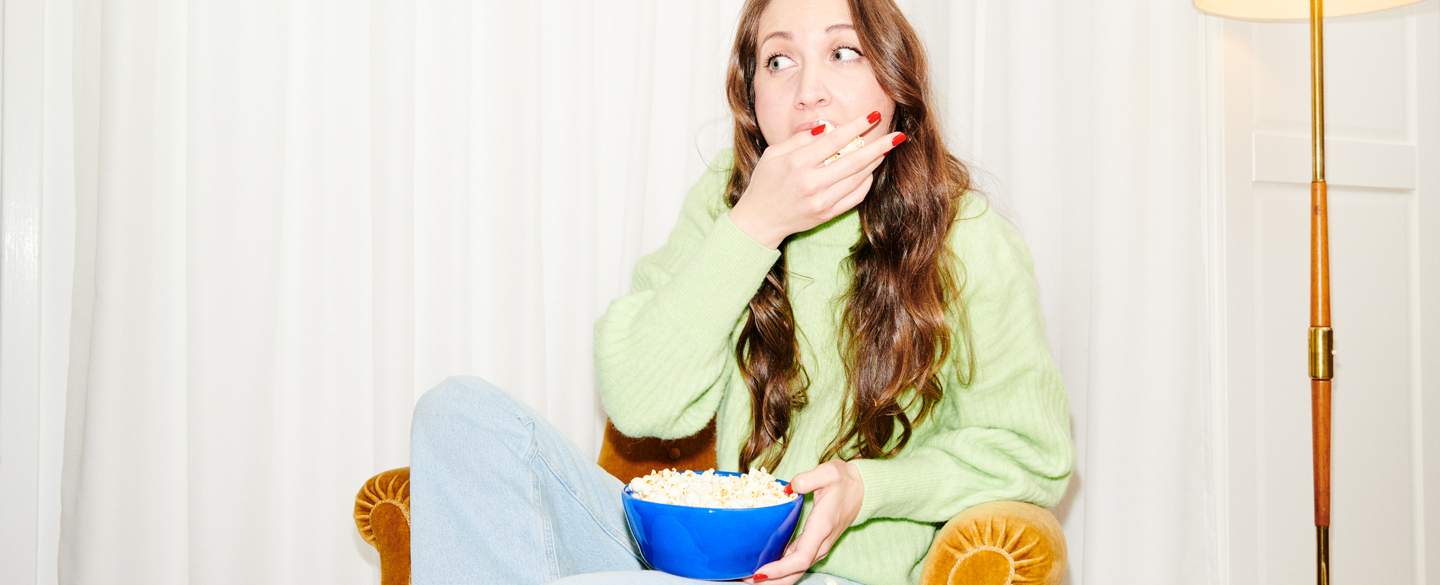 kvinna sitter i en fotölj och äter popcorn
