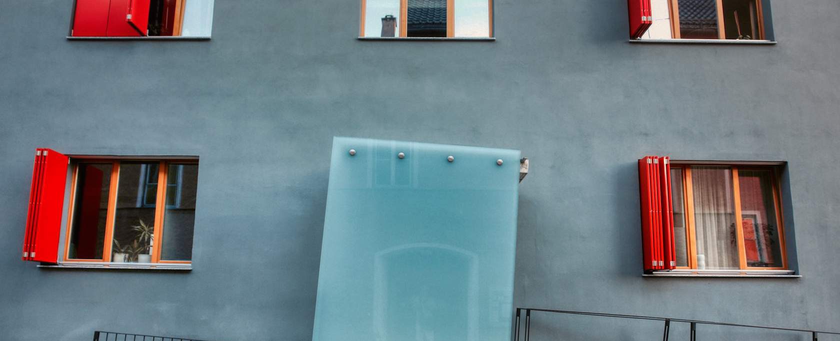 Blå husfasad med fönster med röda fönsterkarmar