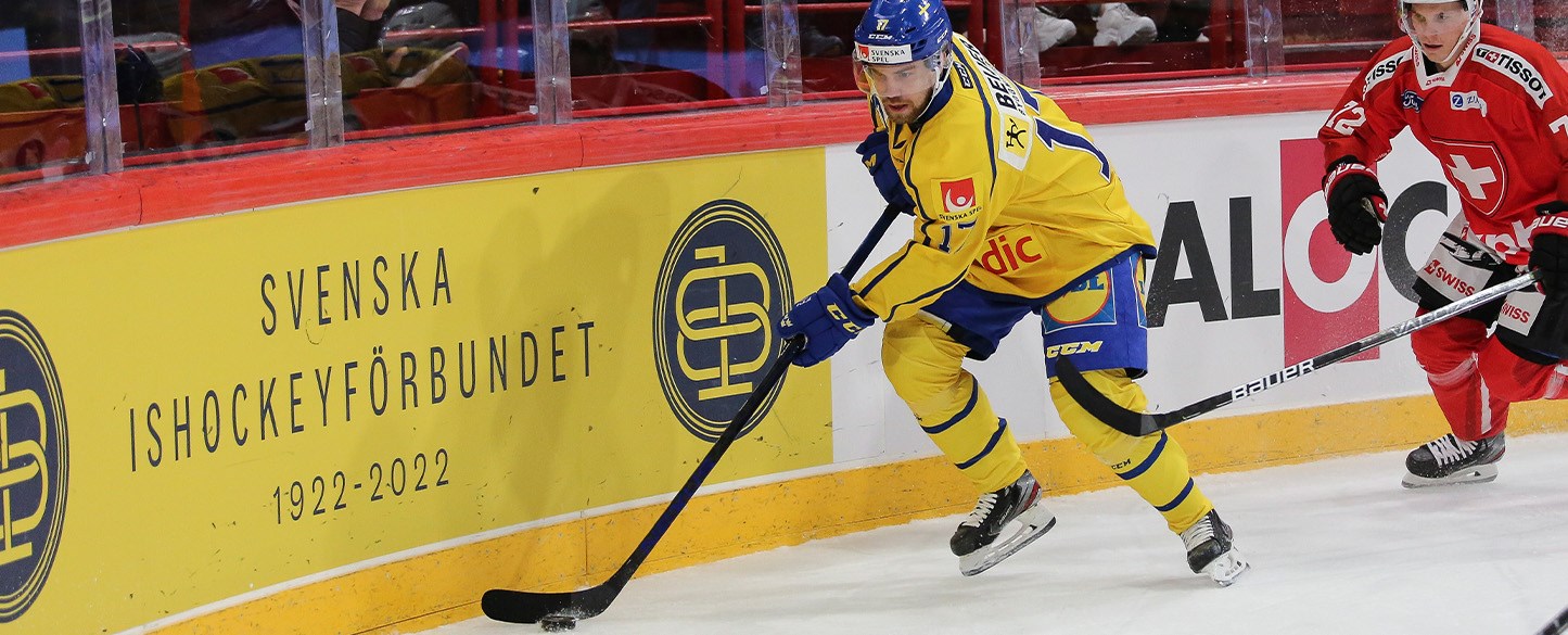 Bilden visar en ishockeyspela re i Tre kronor som har pucken jagad av en motståndare