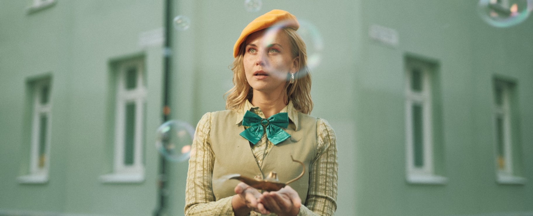 Bild från föreställningen: "Det var en gång ett hus". Kvinna står framför en fastighet