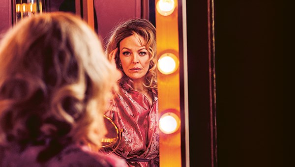 En kvinna tittar på sig själv i en teatersminkspegel