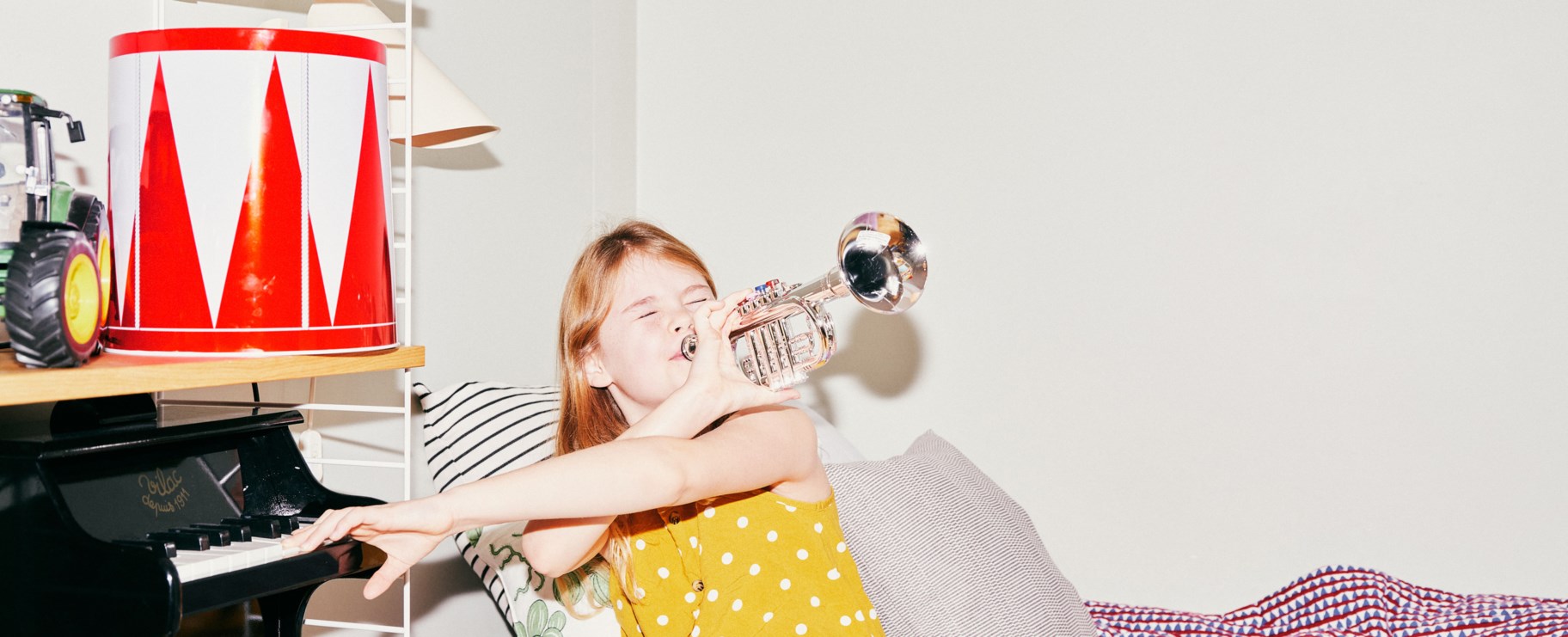 Flicka spelar trumpet på sitt barnrum