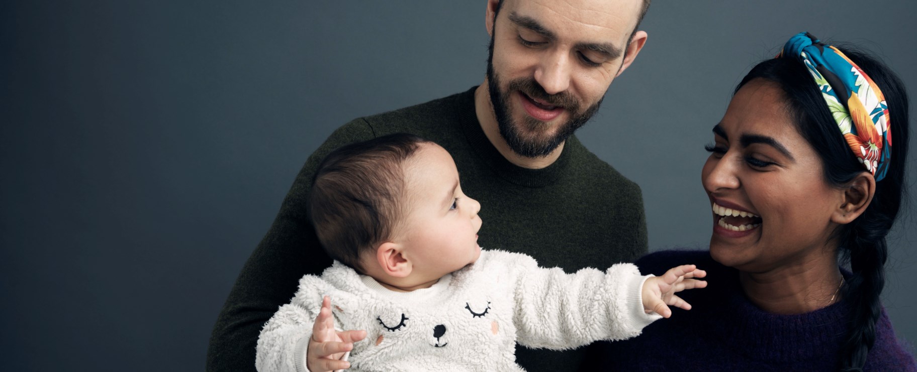 Två föräldrar håller sitt barn i famnen
