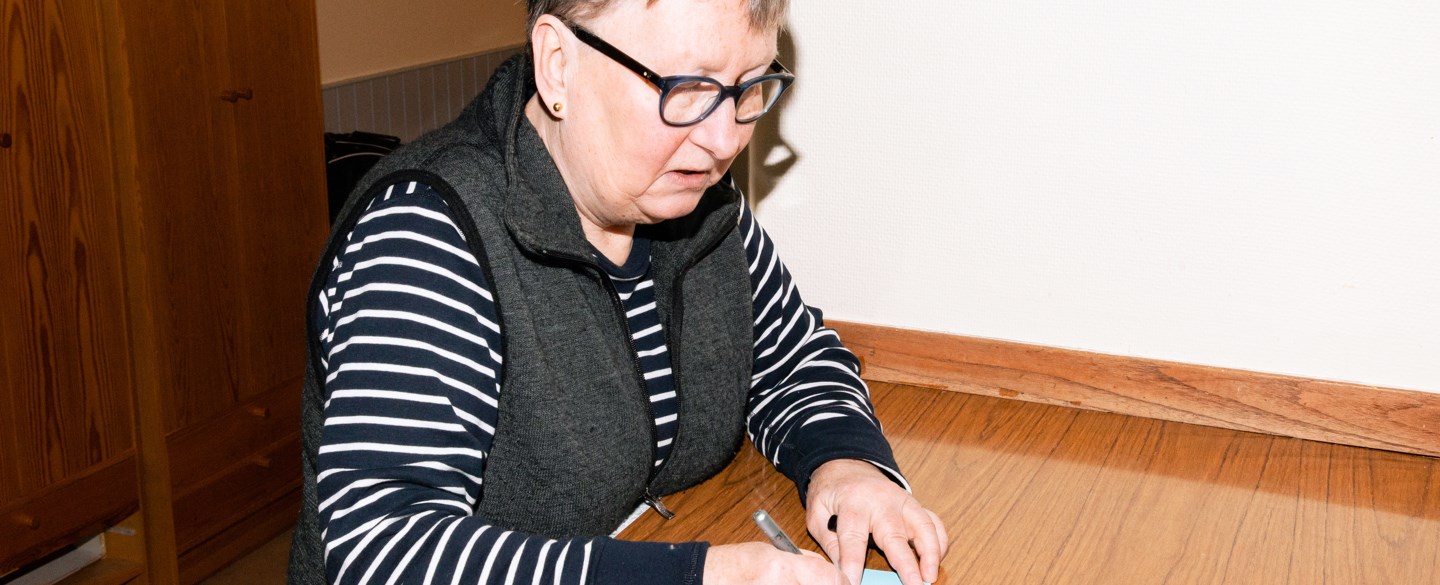 En kvinna skriver ett brev i en av Hyresgästföreningens lokaler.