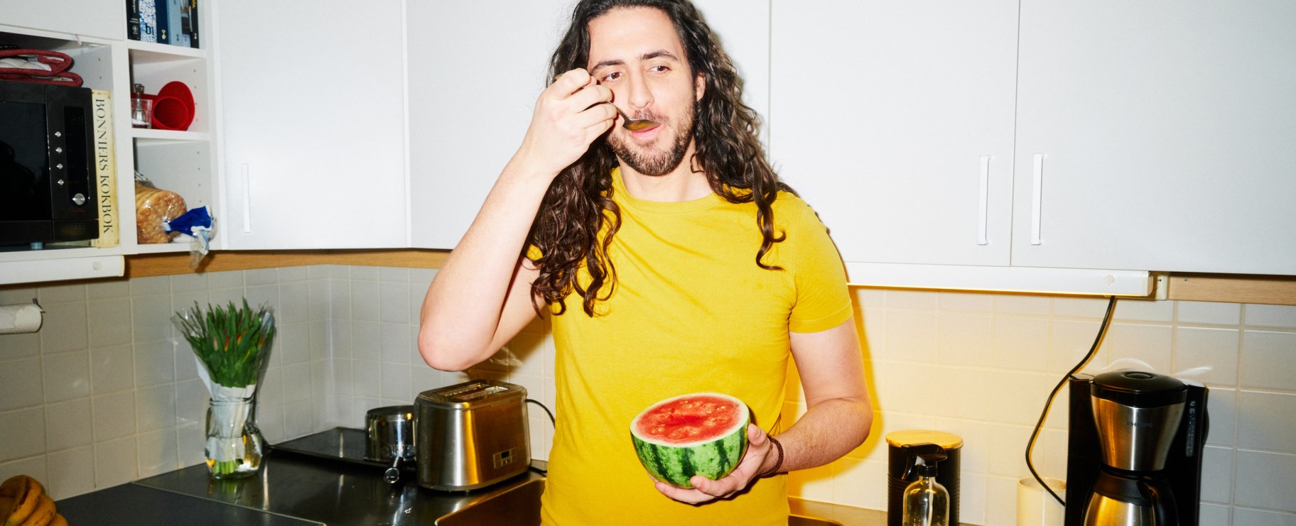 Kille står i kök och äter melon med sked