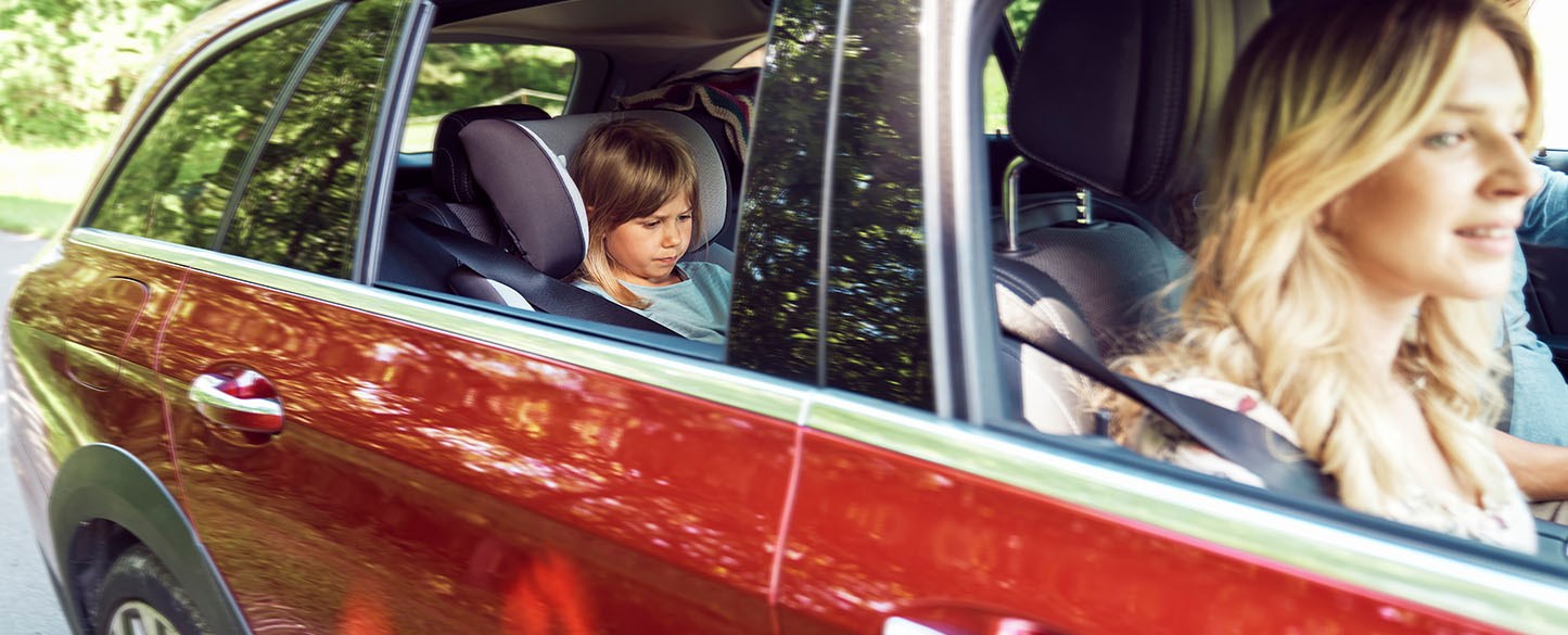 Bilden visar en familj som åker i en röd bil