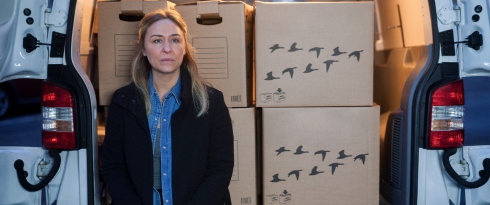 Kvinna sitter i bakluckan vid flyttkartonger