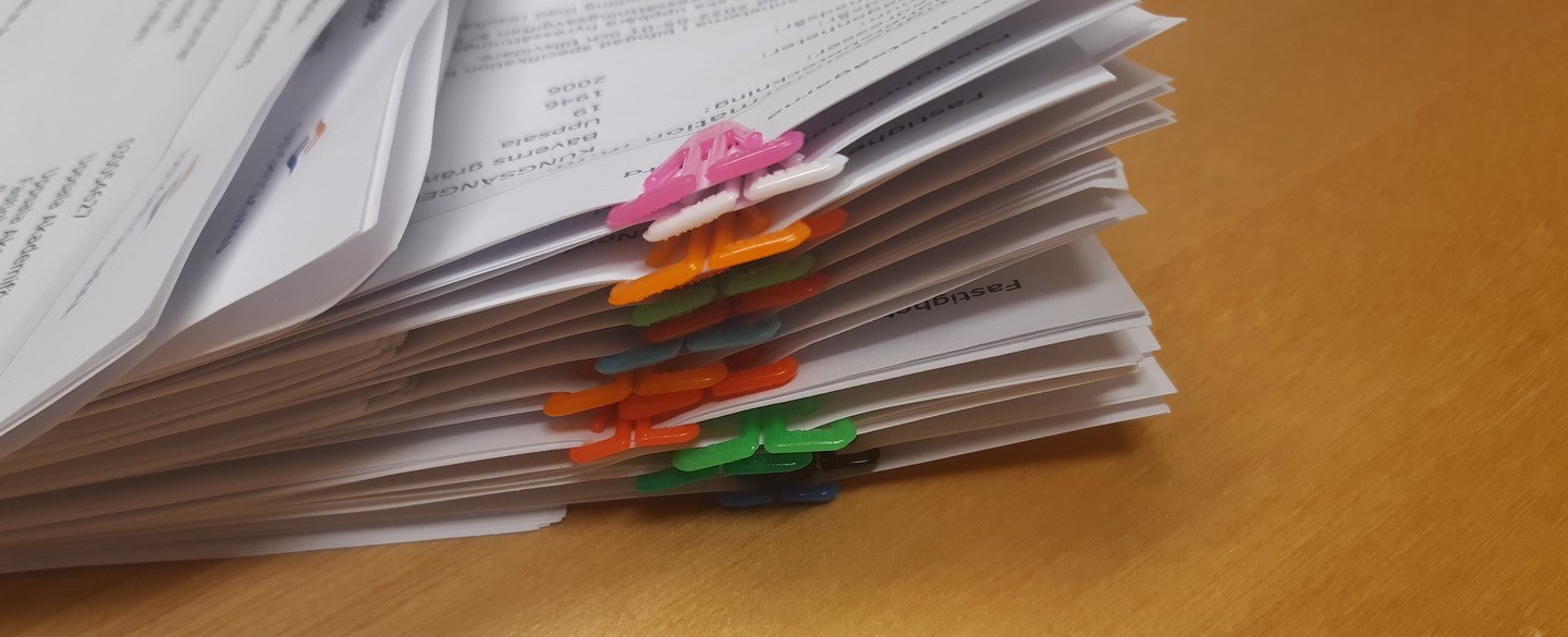 Hög med papper på bord, med färgglada gem