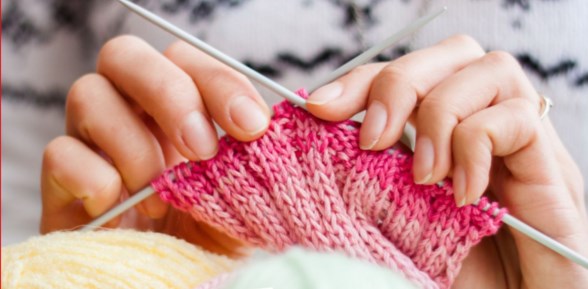 Kvinnas händer håller i rosa stickning