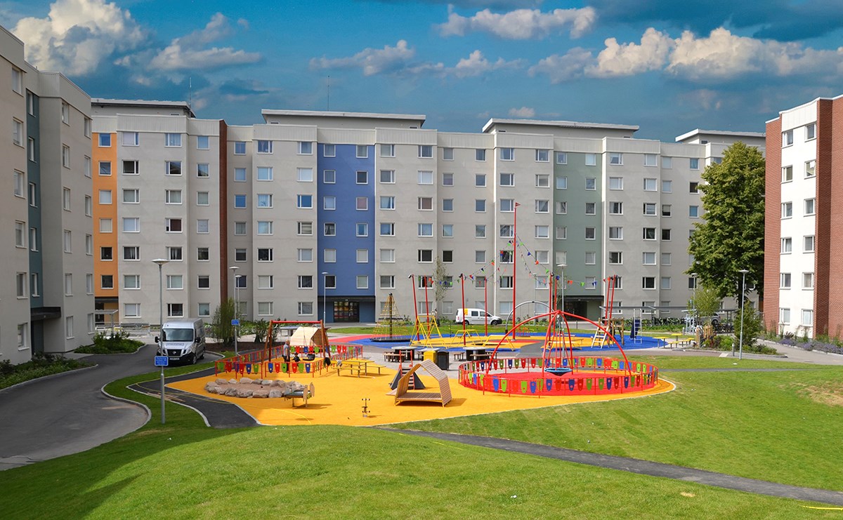 Lekpark på bostadsgård omgiven av färgglada fasader
