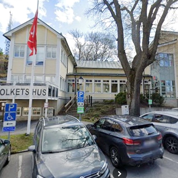 Vy över träbyggnad och parkeringsplats