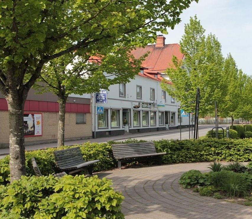 Vy över litet kvarterscentrum med rabatter, träd och hus