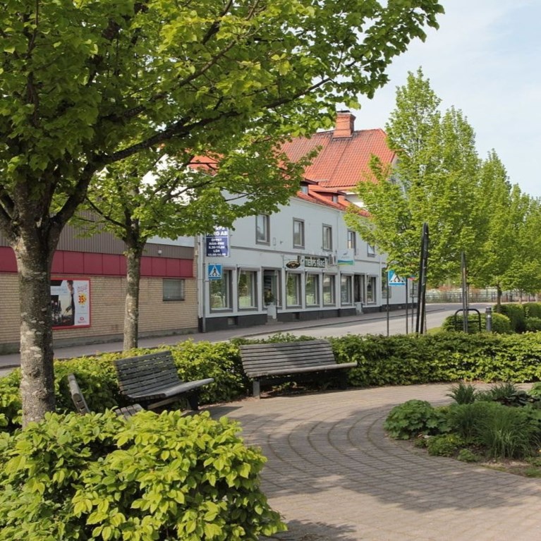 Vy över litet kvarterscentrum med rabatter, träd och hus