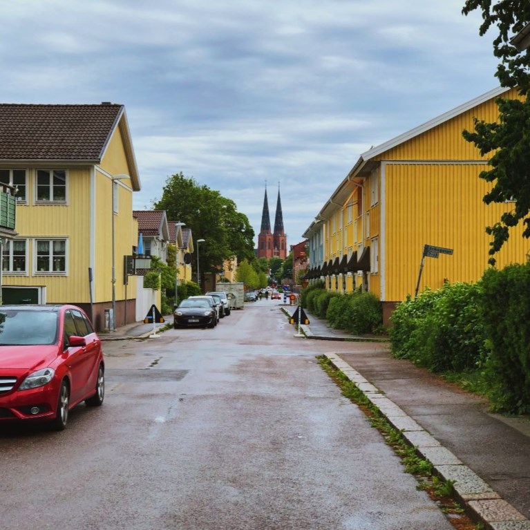 I förgrunden gula trähus och i bakgrunden Uppsala Domkyrka