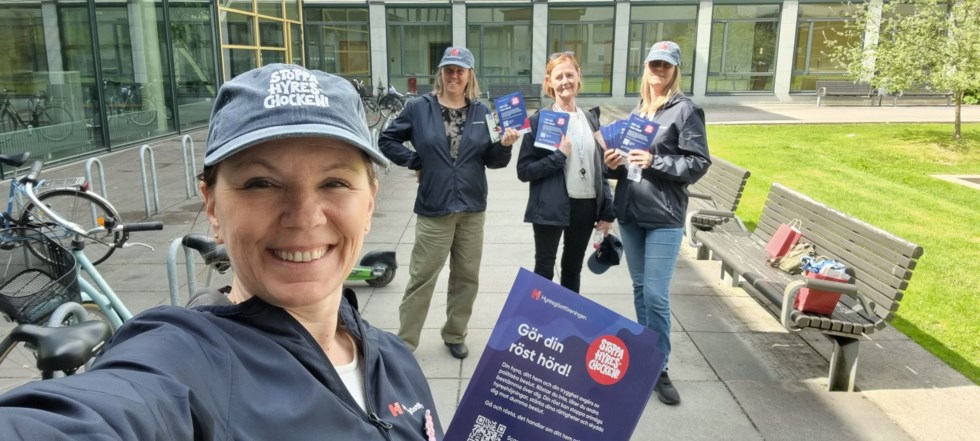 Kvinna i keps tar selfie med vänner i bakgrunden på campusområde