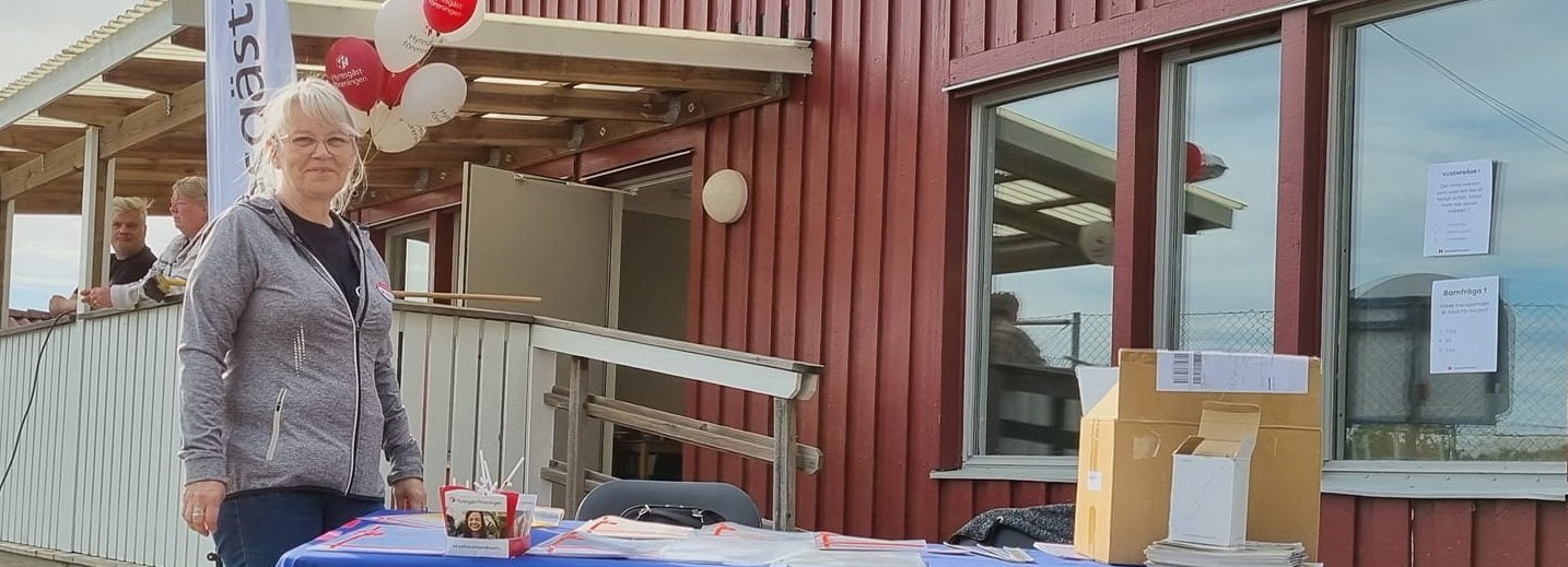 Kvinna står utomhus vid kampanjbord