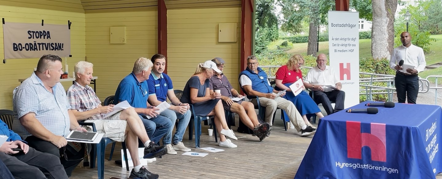 Personer sitter på stolar på en scen.