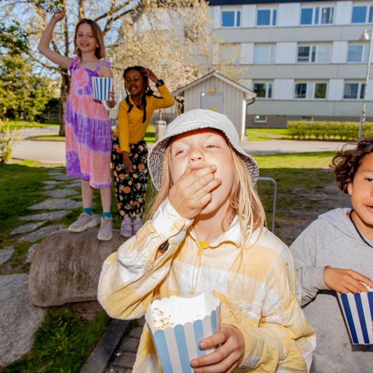 Barn äter popcorn ute på gården