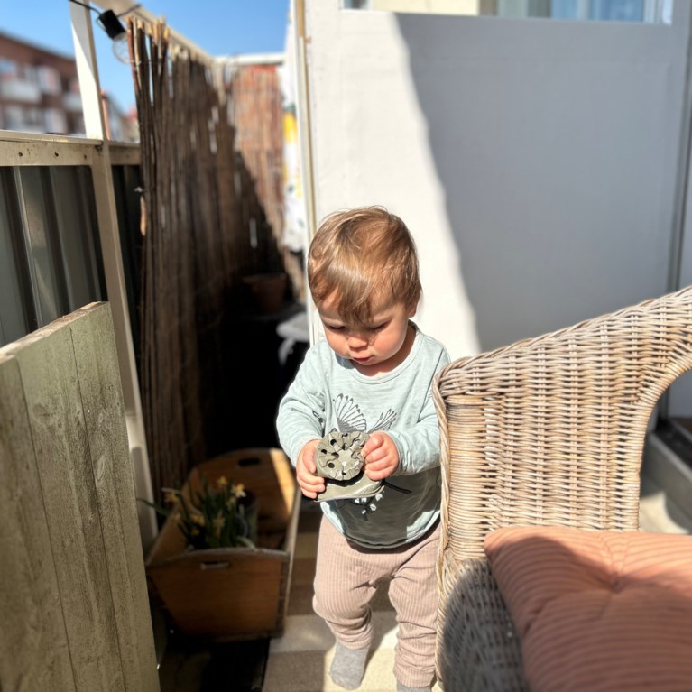 Litet barn håller en odlingskruka på balkongen