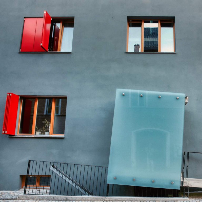 En blå husfasad med fönster med orange fönsterkarmar.