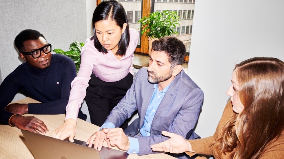 Personer som står vid en dator och tittar på skärmen