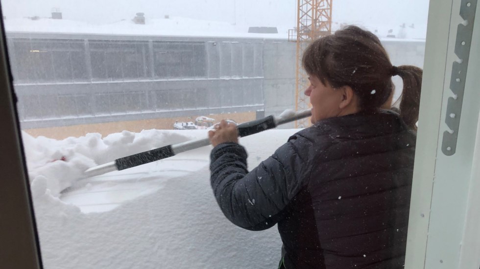 Kvinna skotta snö på balkongen