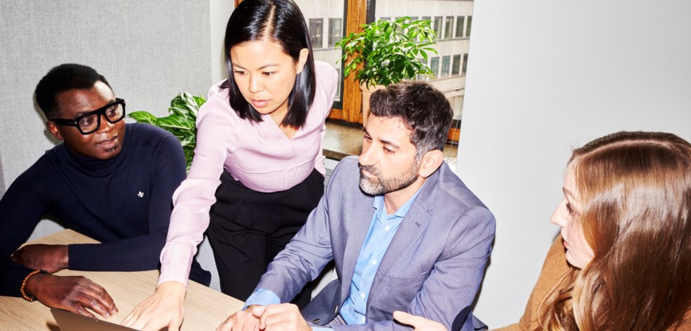 Två män och två kvinnor tittar på en dator under förhandling