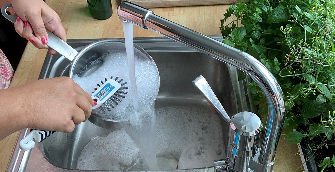 En kvinna diskar en panna under rinnande vatten