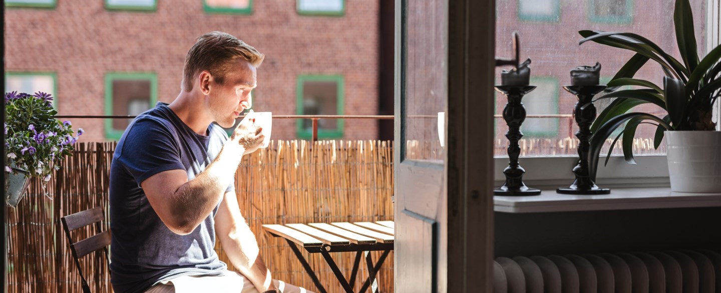 Man dricker kaffe på balkong