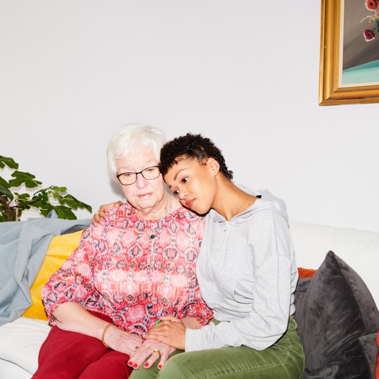 Äldre kvinna och en yngre kvinna sitter tillsammans i en soffa