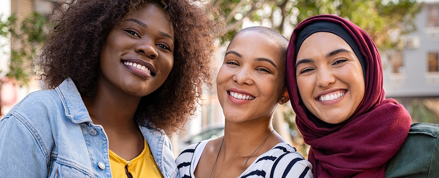 Tre tjejer som ler mot kameran