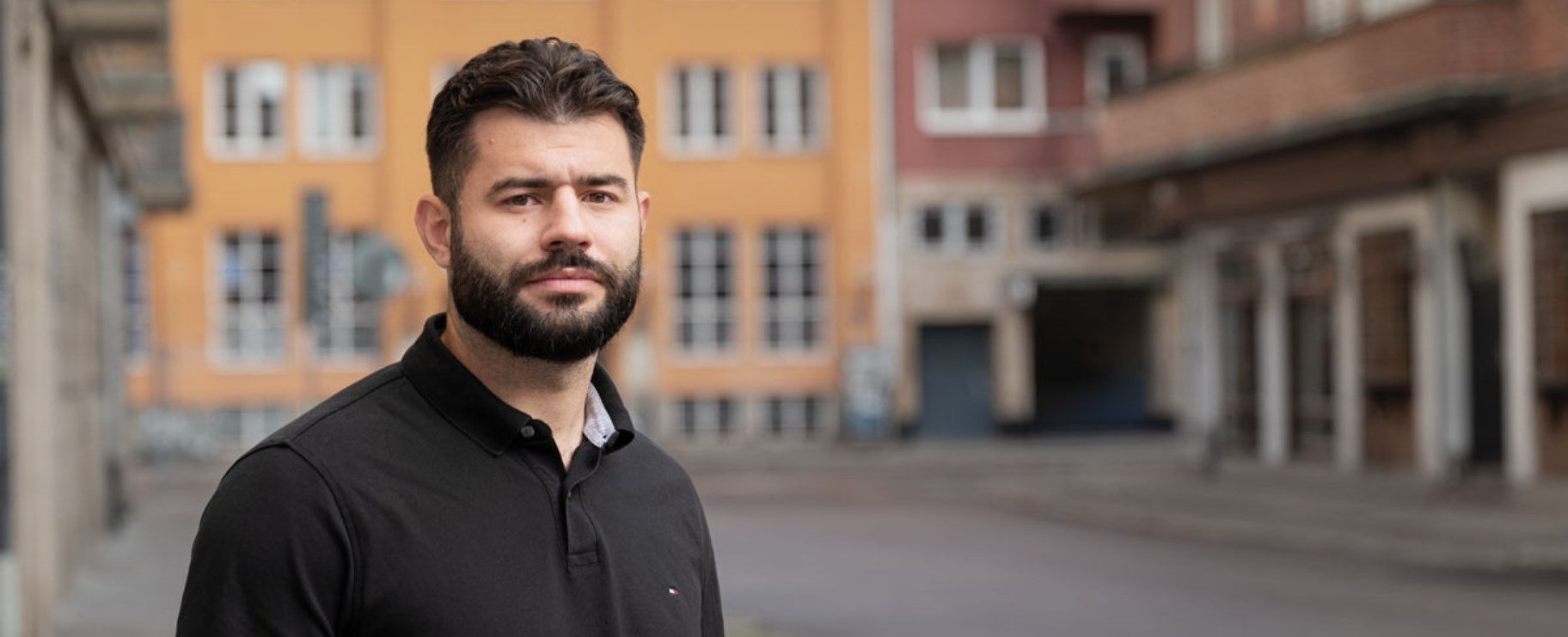 Bild på en man med skägg som tittar in i kameran.