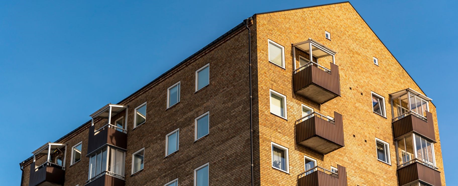 En gul lägenhetsfastighet med bruna balkonger.