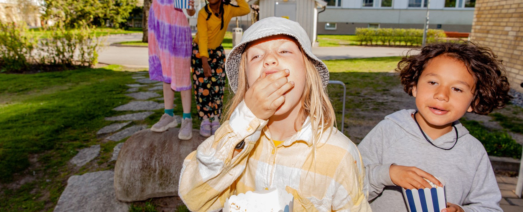 Barn ute på gården och äter popcorn.
