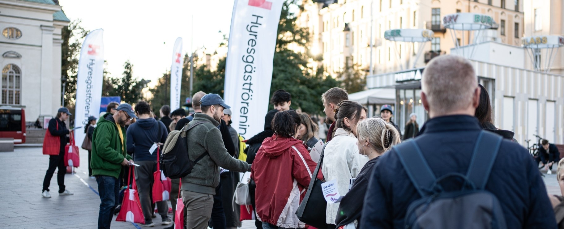 Människor står i kö på ett torg.