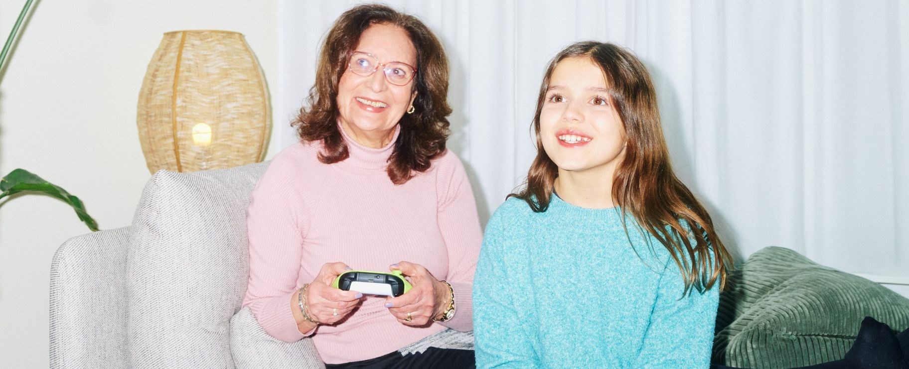 Äldre dam spelar tv-spel med ung flicka.