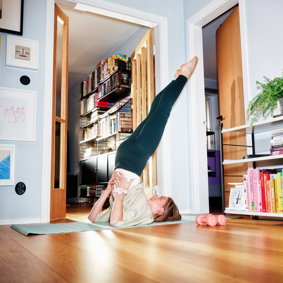 Kvinna tränar yoga hemma i lägenheten.