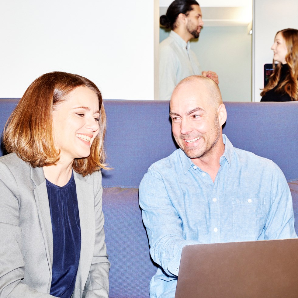 Två glada personer sitter vid datorn.