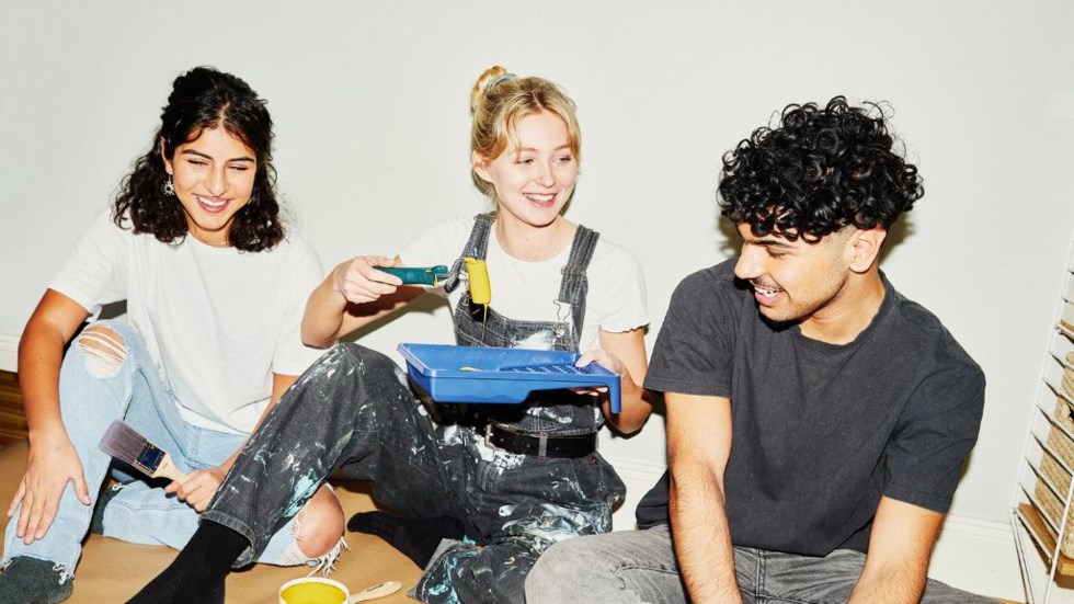 Tre glada ungdomar som målar.