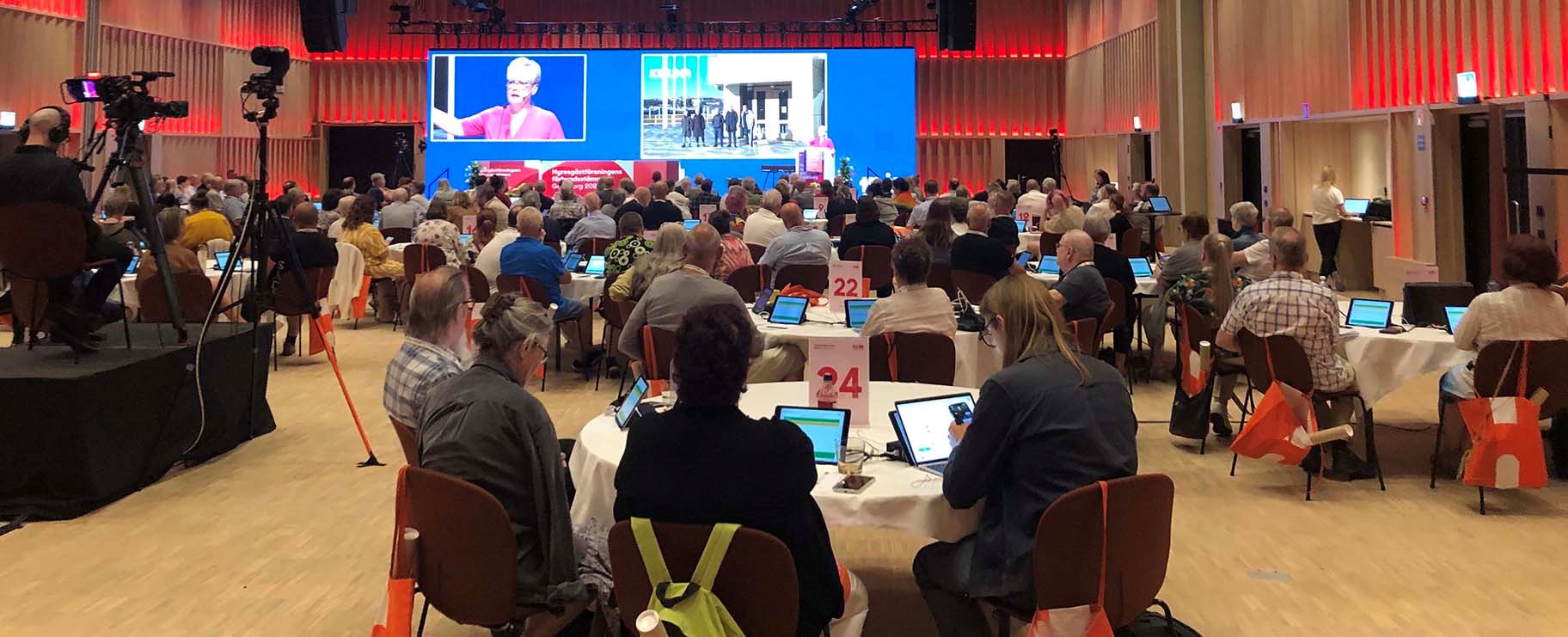 Foto från stämmosalen i Göteborg 2023. På bilden syns ombud som sitter runt runda bord och kollar mot scenen.