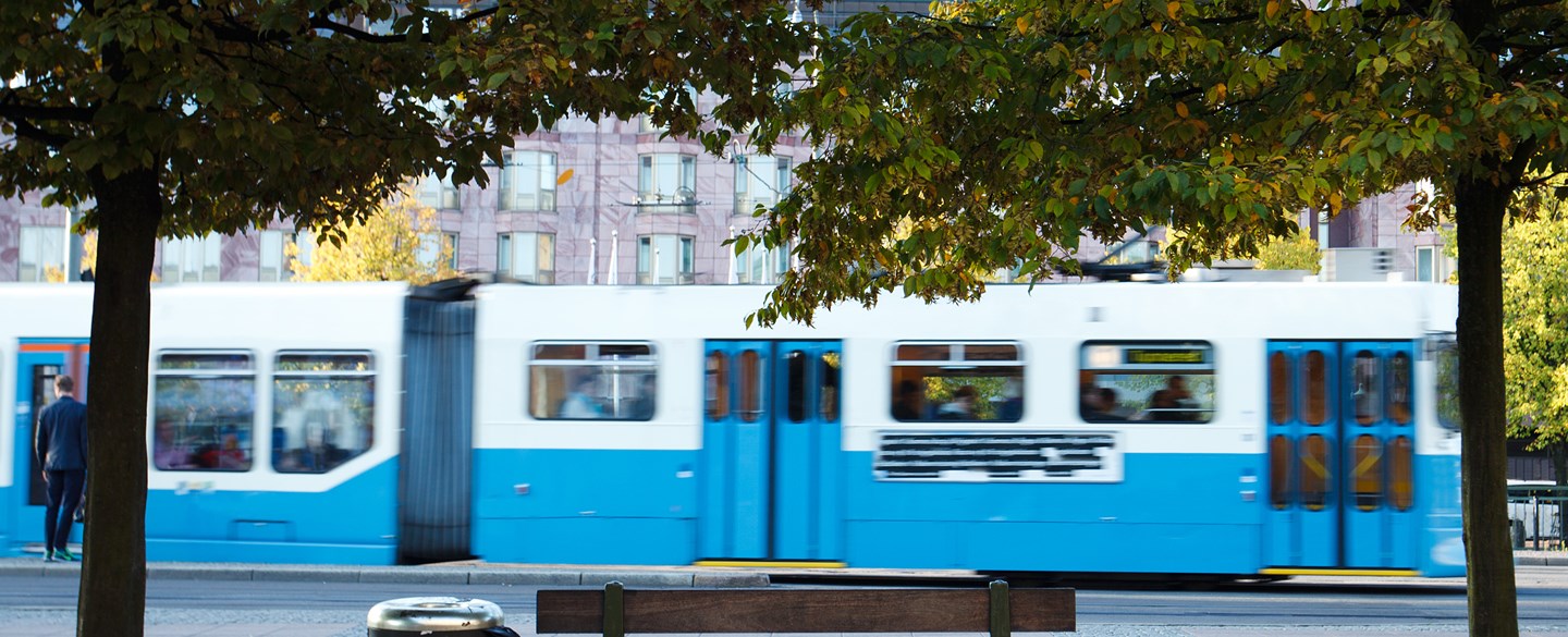 Foto på en spårvagn med träd i förgrunden