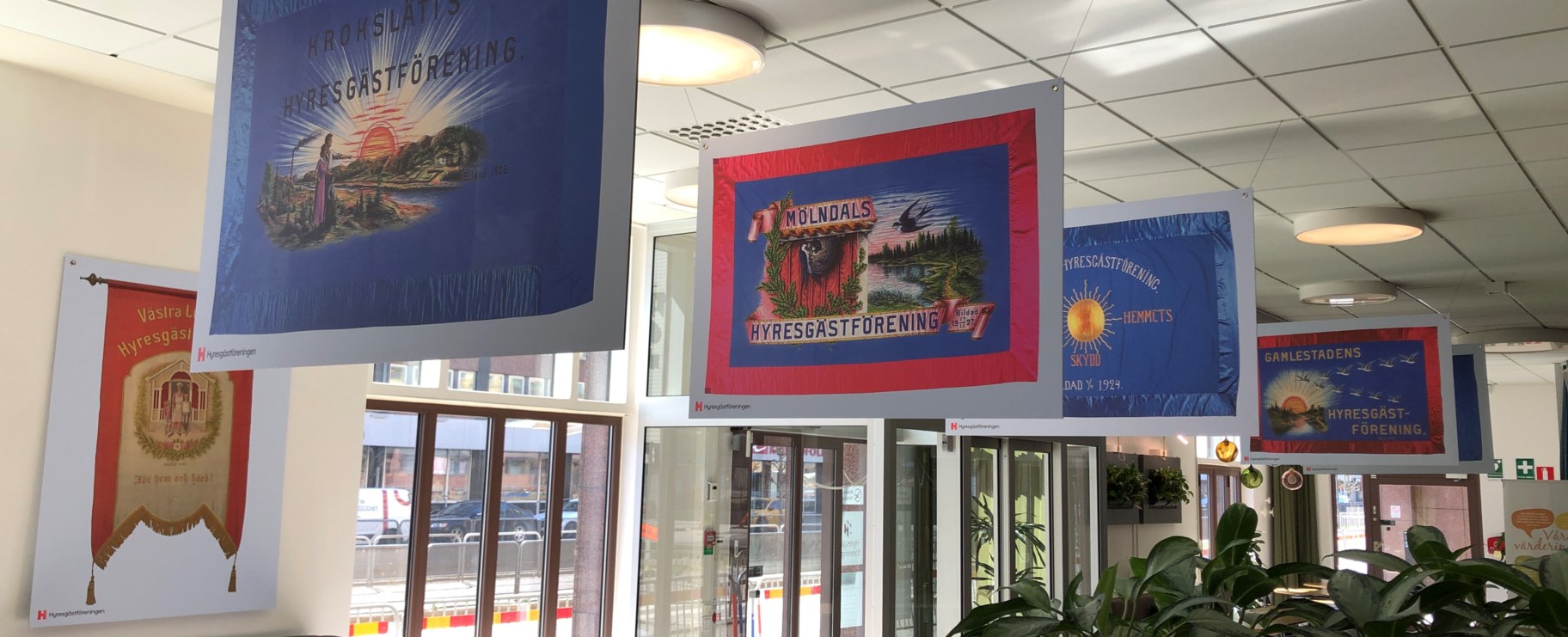 Foto inne i entrén där man ser skyltar som hänger från taket på fanor  från föreningar i regionen.