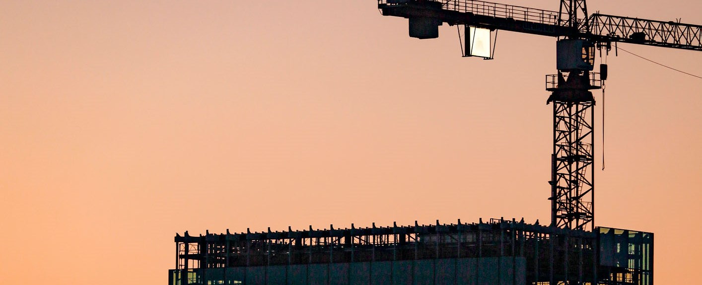 En lyftkran och ett hus i skymningen