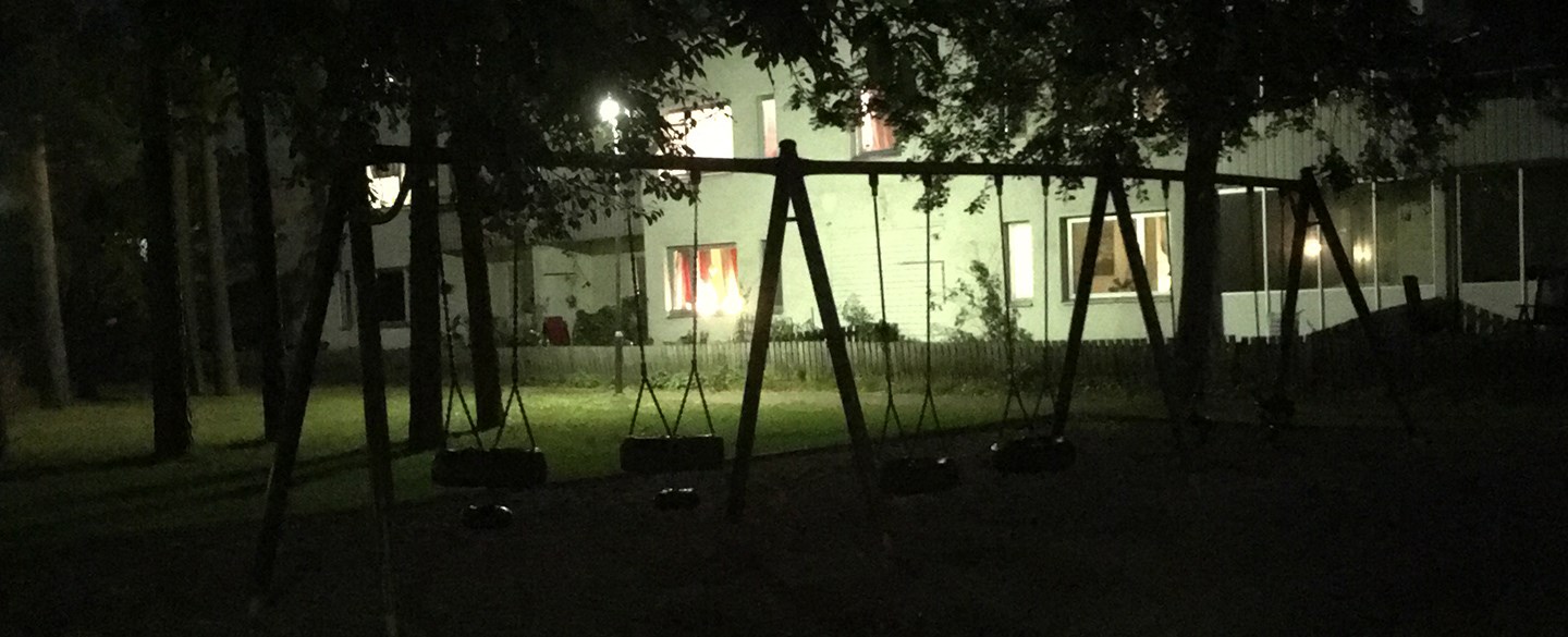 Husfasad och gungor i mörkret