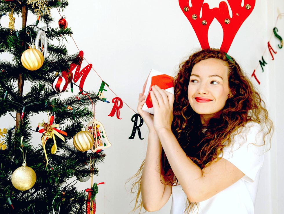 Bild på glad person framför en julgran