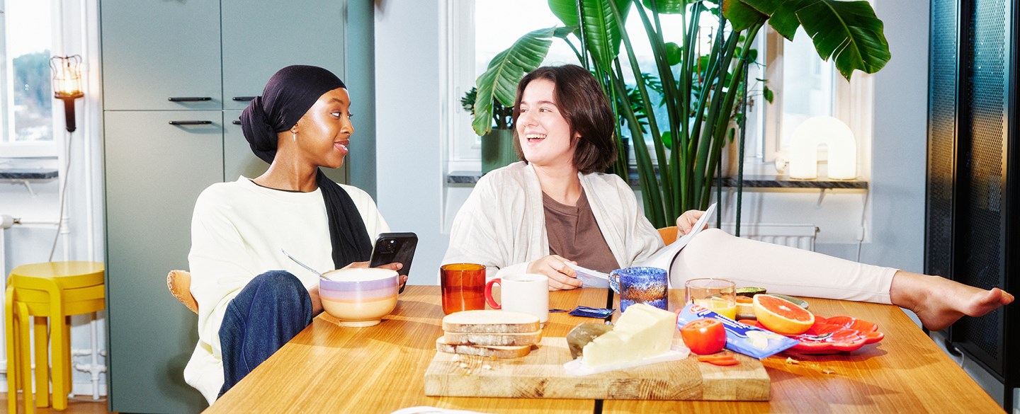 två unga kvinnor äter frukost vid köksbordet