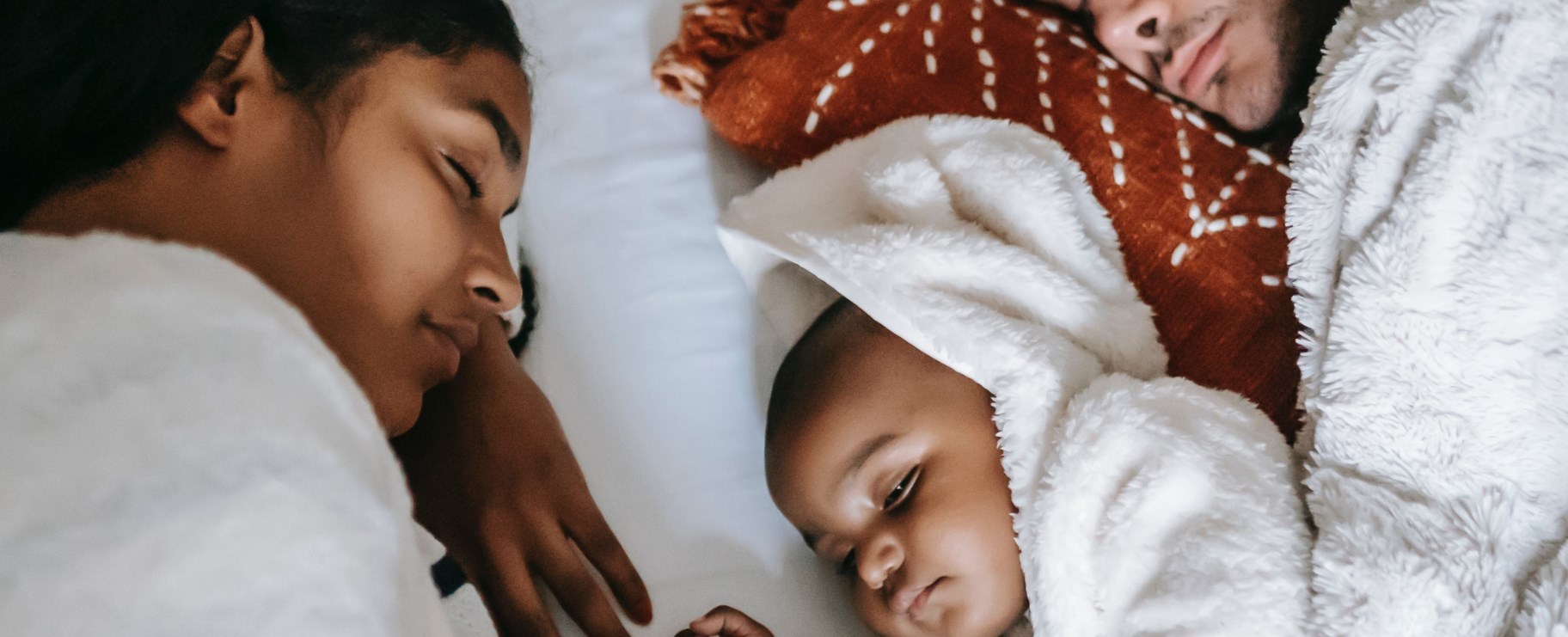 föräldrar vilar i sängen med bäbis