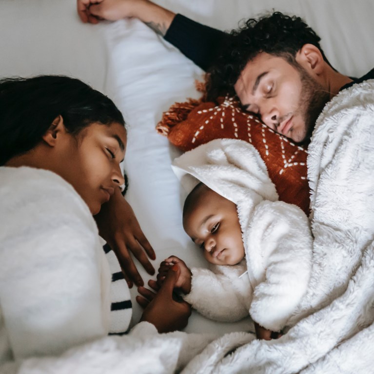 föräldrar vilar i sängen med bäbis