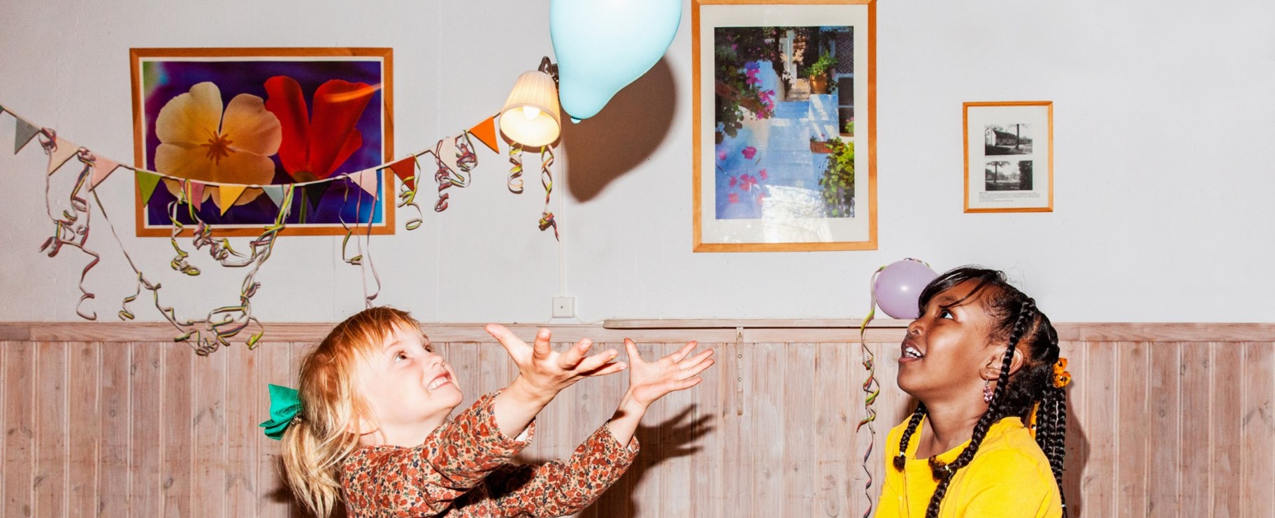 Två barn på ett kalas som kollar på en blå ballong i luften