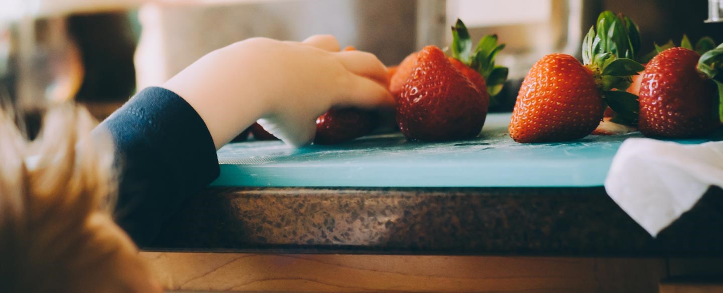 En barnhand som tar en jordgubbe